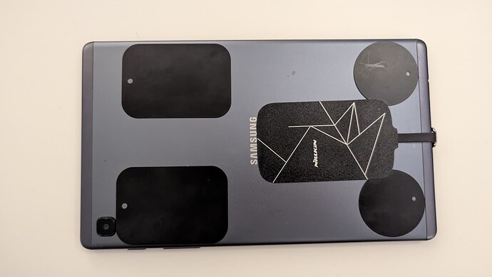 The back of the tablet, with ferrous stickers and charging adapter